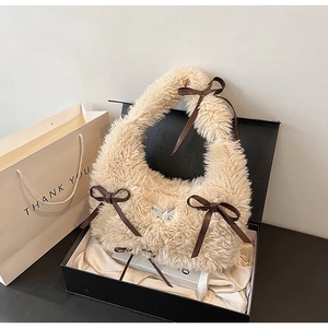 Dettaglio borsa di peluche color albicocca con fiocchi marroni e ciondolo a farfalla