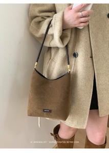 Detail of a brown suede bucket bag with NO FILTER label on a beige wool coat outfit