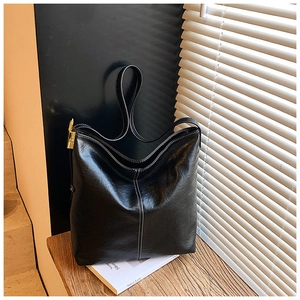 Détail du sac cabas noir en cuir ciré avec surpiqûres blanches et boucle dorée élégante