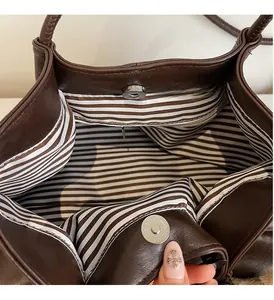 Détail de cabas en cuir marron avec boucle magnétique et doublure en tissu rayé