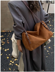 Detail of caramel suede shoulder bag showing leather strap and buckle on model back
