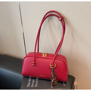 Détail du sac bowling en cuir rouge avec fermeture éclair dorée et logo gaufré chic
