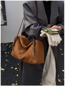 Close-up of brown suede pillow tote bag with leather strap and golden buckle detail