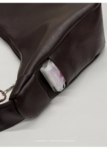 Detail view of deep brown hobo bag side pocket showing functional storage capacity
