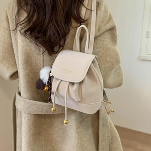 Detail of a beige mini backpack with drawstring closure and cute heart plush charm