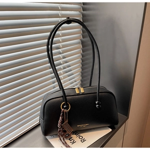 Détail du sac en cuir grainé noir avec fermetures dorées et pendentif boulier élégant