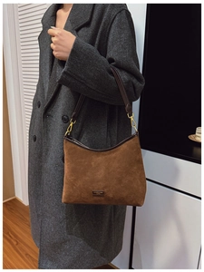 Borsa hobo in camoscio marrone con tracolla indossata su un cappotto di lana grigio
