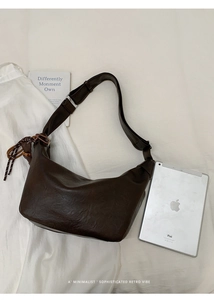 Minimalist retro dark brown crossbody bag next to an iPad showing large capacity