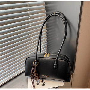 Détail du sac bowling en cuir grainé noir avec zip doré et pendentif tressé