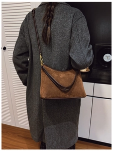 Borsa tote in camoscio marrone con finiture in pelle indossata da modella in un interno