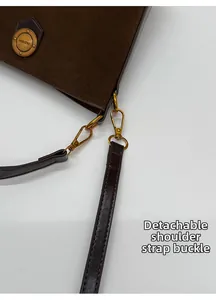 Close-up of golden metal clasp on brown suede bucket bag with a detachable leather strap