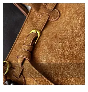 Close-up of vintage brown leather bucket bag showing fine stitching and metal buckle details
