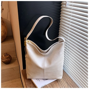 Détail d'un sac seau blanc crème en simili cuir avec couture verticale et boucle en métal