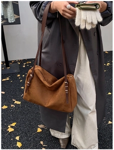 Detail of brown suede pillow bag featuring slim leather straps and gold buckle accents