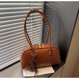 Détail du sac bowling en cuir marron avec fermeture éclair dorée et pendentif en cuir