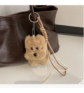 Vue détaillée d'un charm de sac chiot pelucheux avec chaîne en métal sur sac en cuir