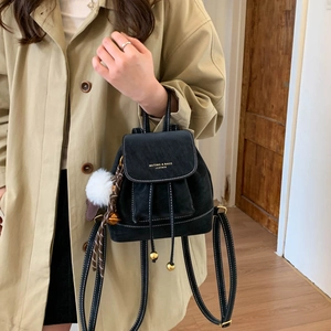 Detail of black mini leather backpack with gold logo, drawstring and plush charm