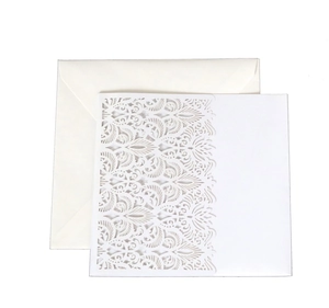 Macro view of white laser-cut wedding invitation with intricate Damascus hollow patterns