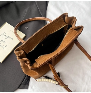 Top view of brown suede bucket bag with wooden bead charm and golden zipper detail
