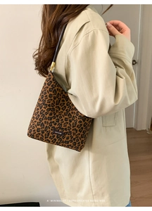 Detail of leopard print shoulder bag with NO FILTER label worn on a beige coat