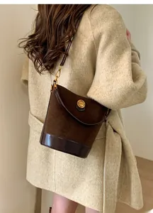 Detailed close-up of dark brown suede bucket bag with gold fashion metal buckle
