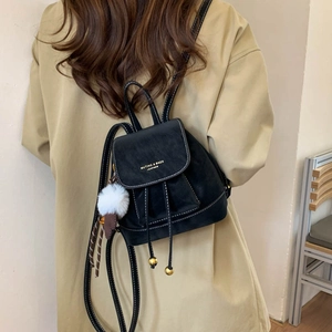 Detail of black drawstring backpack with contrast white stitching and fluffy pom-pom charm