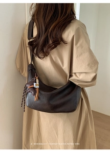 Detail of dark brown dumpling bag with bear charm worn with khaki trench coat