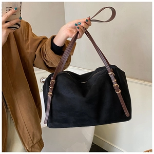 Detail view of black faux suede Boston bag with adjustable brown leather straps and gold hardware