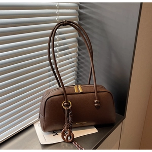 Détail du sac bowling en cuir marron foncé avec fermeture éclair dorée et pendentif
