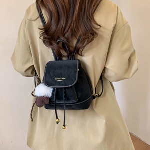Detail of black leather mini backpack with drawstring closure and white stitching accents