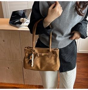 Close-up of vintage brown matte bucket bag with buckle detail and beaded charm