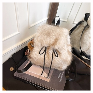Detail eines beigen Kunstpelz-Rucksacks mit schwarzem Kordelzug und seitlichem Pompon-Dekor