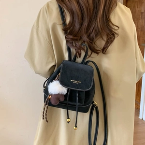 Detail of black mini backpack featuring white contrast stitching and plush heart charm