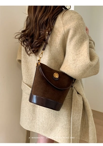 Detail of retro suede bucket bag showing golden FASHION buckle and premium texture
