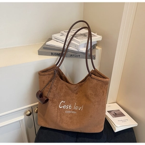 Close-up of brown suede tote bag with white embroidery on minimalist studio background