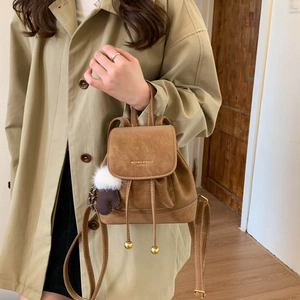 Detail of vintage brown leather backpack with drawstring closure and pompom charm
