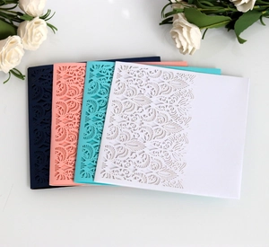 Detail of laser-cut wedding invitations showing intricate leaf patterns in four colors