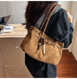 Detailed view of vintage brown suede bucket bag with decorative wooden bead tassel accent
