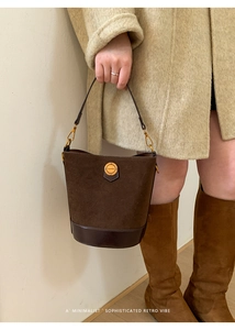 Detail of vintage suede bucket bag with gold fashion buckle and premium textured finish