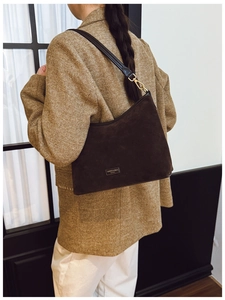 Dettaglio della borsa hobo in pelle scamosciata marrone scuro con placca in metallo dorato
