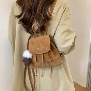 Close-up of brown leather backpack with drawstring closure and golden logo detail