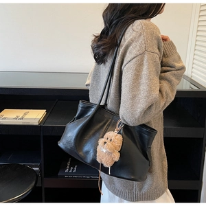 Détail d'un grand sac cabas noir orné d'un pendentif en peluche petit chien marron
