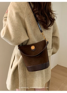Rear view of model wearing a vintage dark brown suede bucket bag with gold hardware