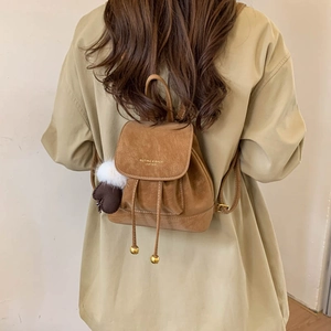 Close-up of a brown mini backpack featuring drawstring closure and a plush heart charm