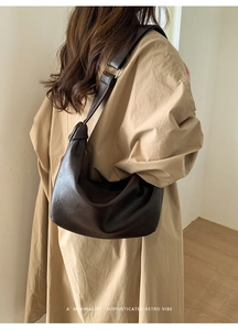 Detail of dark brown leather hobo bag with a minimalist knotted shoulder strap design