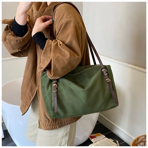 Macro detail of dark green suede shoulder bag featuring a brown leather strap and gold buckle