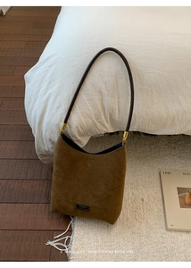 Close-up of brown suede hobo bag with round shoulder strap and gold metal hardware