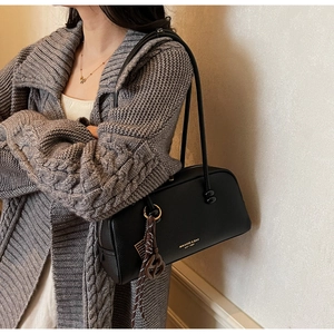 Detail of black leather pillow bag with gold hardware and silk scarf on grey cardigan