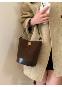 Detail of vintage brown suede bucket bag with gold fashion buckle and smooth leather base