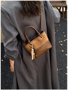 Detail of vintage patchwork crossbody bucket bag with beads on a grey blazer outfit